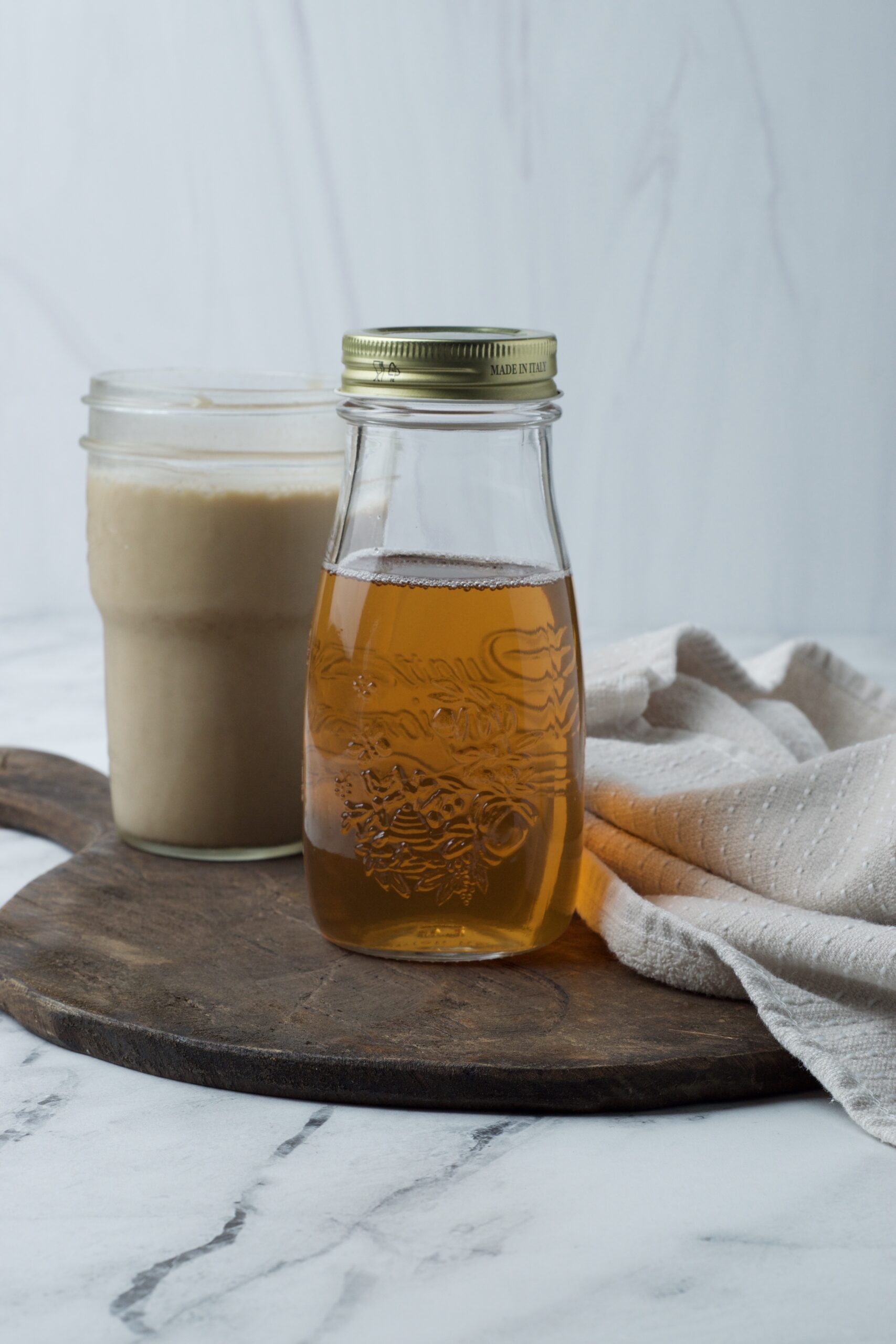 Jar of vanilla syrup sitting next to iced latte and napkin